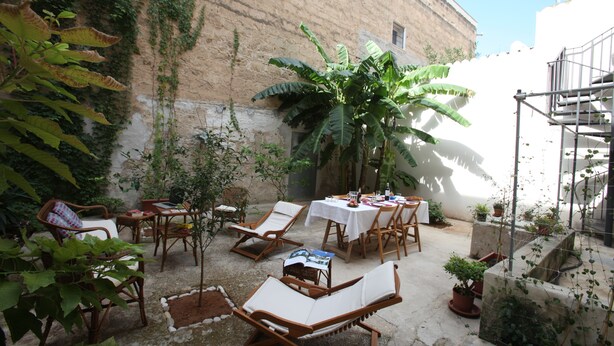 A patio area with outdoor seating, a table set for dining, and potted plants. - B&B La Casa di Paola (Trapani)