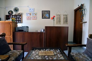 A reception area with a wooden desk, a glass display case with shells, and a framed portrait on the wall. - Feeloxenia Corfu Apartments (Corfu)