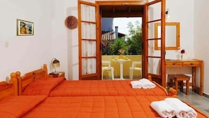 A bedroom with an open door leading to a balcony, a bed with orange bedding, a bedside table, and a desk with a chair. - Feeloxenia Corfu Apartments (Corfu)