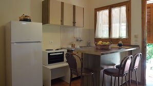 A compact kitchen with a refrigerator, oven, and a small dining area with two chairs. - Feeloxenia Corfu Apartments (Corfu)