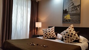 A hotel room with a bed, a nightstand, a lamp, and a painting of a yellow scooter. - InnVatican (Rome)