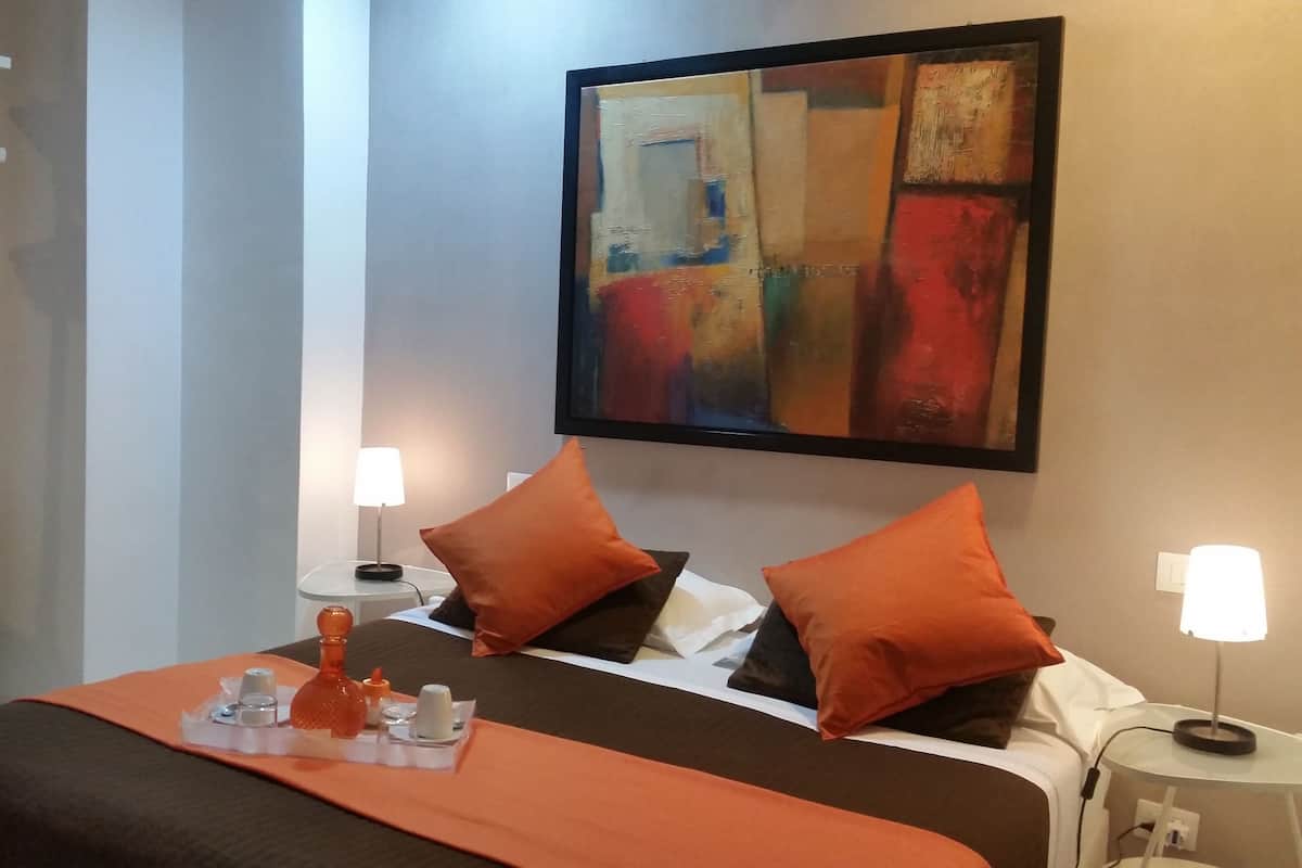 Una camera d'albergo con un letto, due comodini, un armadio e un quadro.