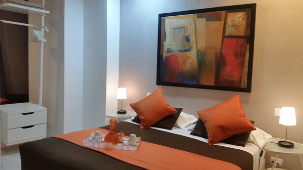 A hotel room with a bed, two bedside tables, a nightstand, a painting, and a wardrobe. - InnVatican (Rome)