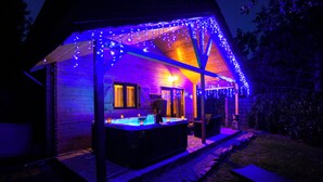 Un espace avec un jacuzzi, une terrasse en bois et des guirlandes lumineuses.