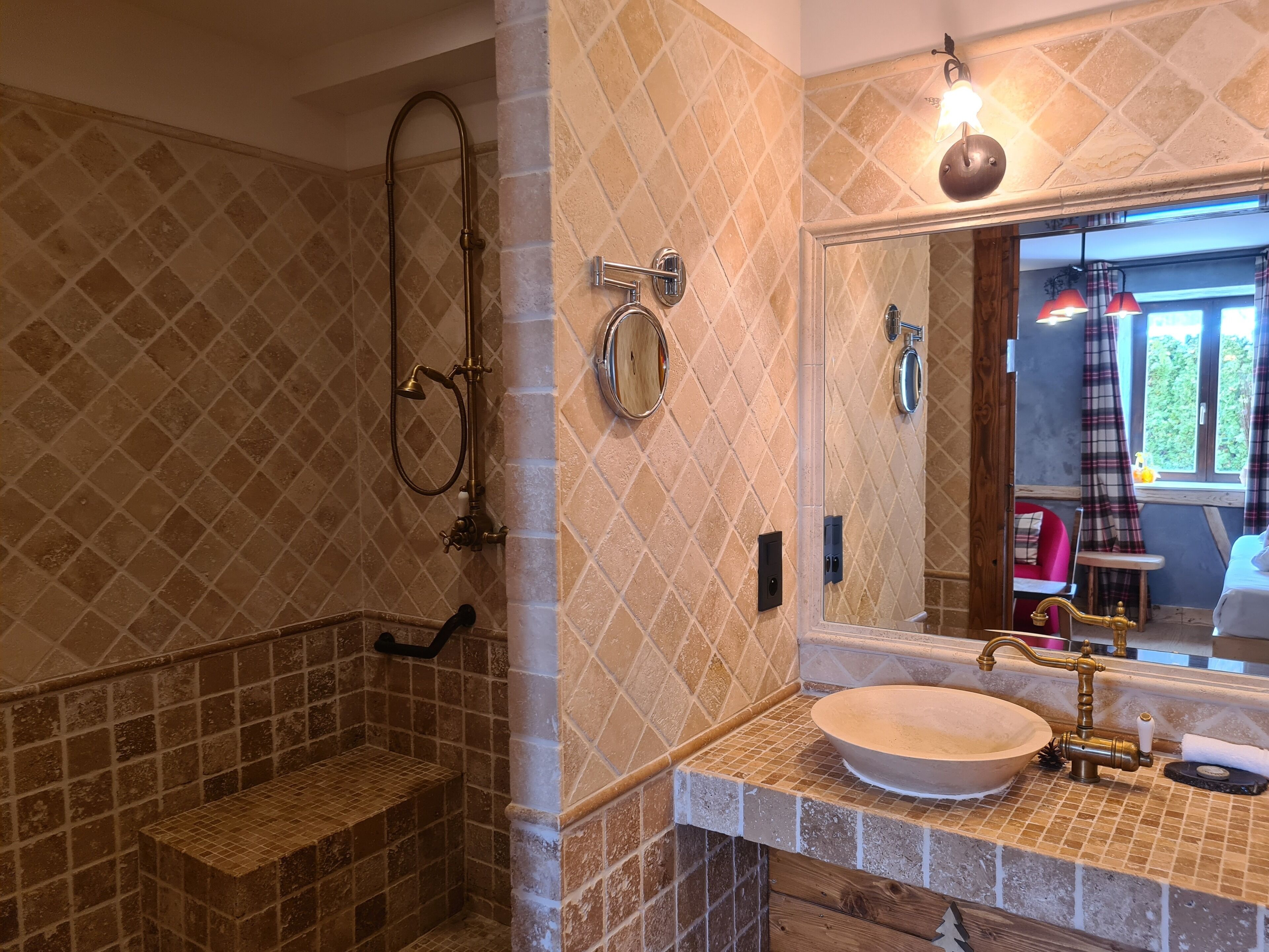 A bathroom with a shower, a sink with a brass faucet, and a mirror.
