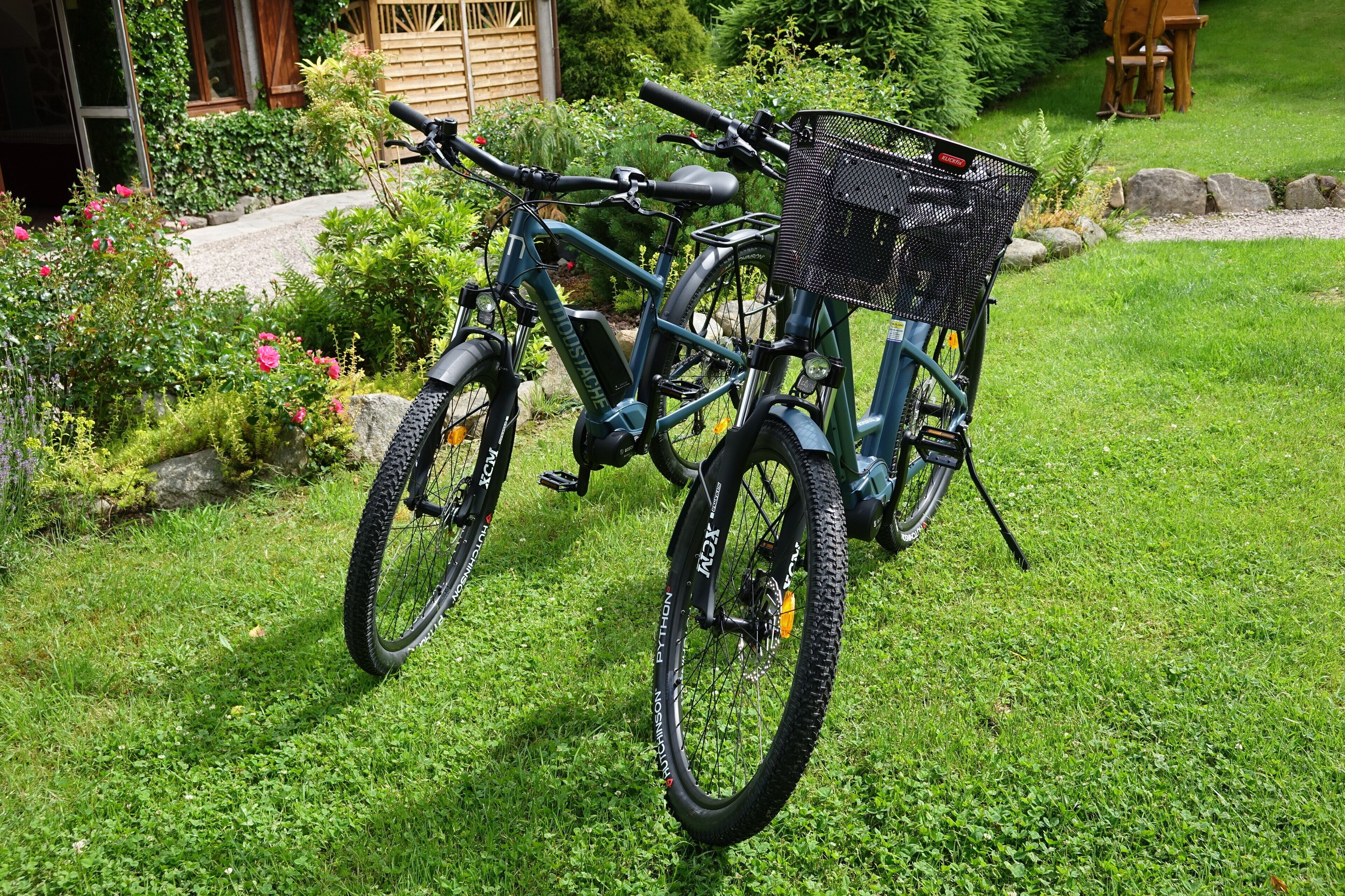 A stationary bicycle with a basket, parked on a grassy lawn.