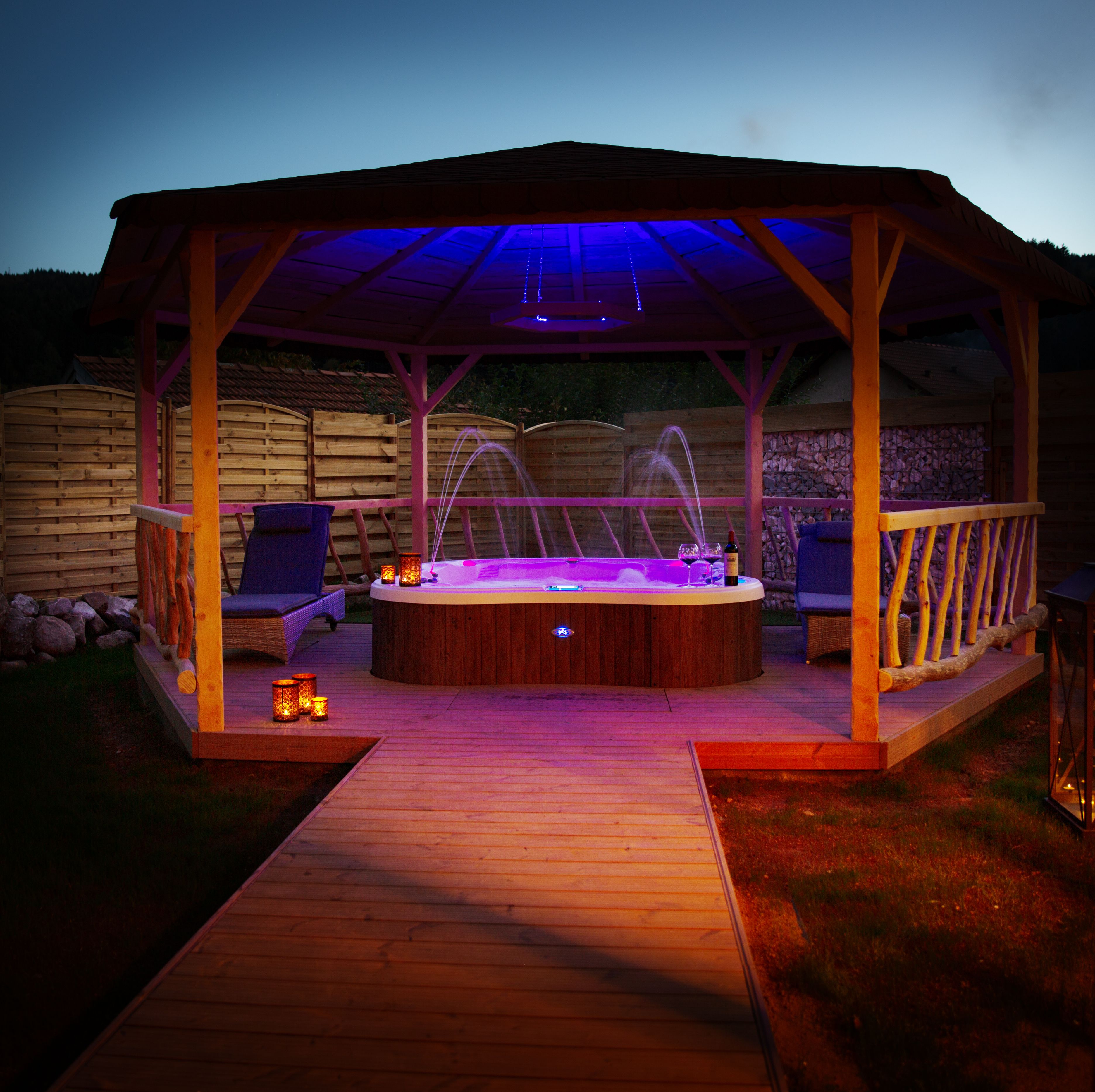A wooden hot tub with a canopy, surrounded by a deck and lounge chairs.