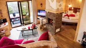 Une pièce confortable avec une cheminée, un lit, une télévision et un coin repas comprenant une table et des chaises.