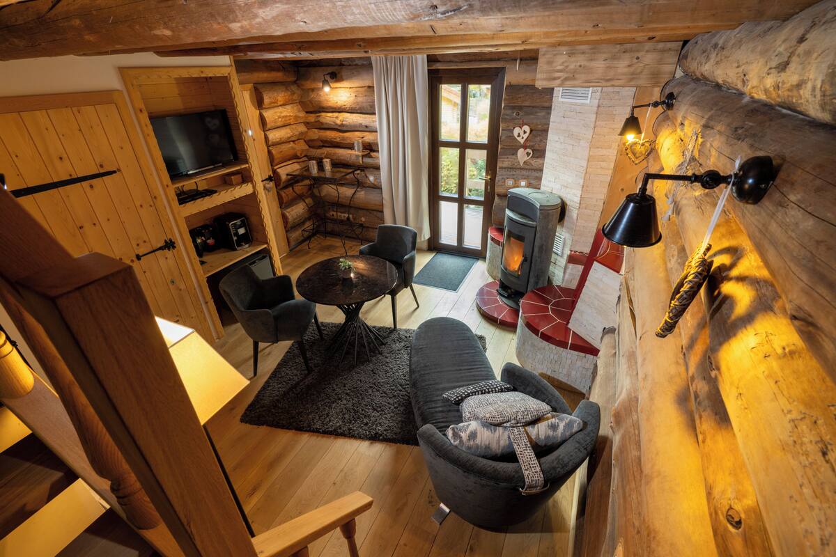 A log cabin interior with a cozy living area, a fireplace, and a television.
