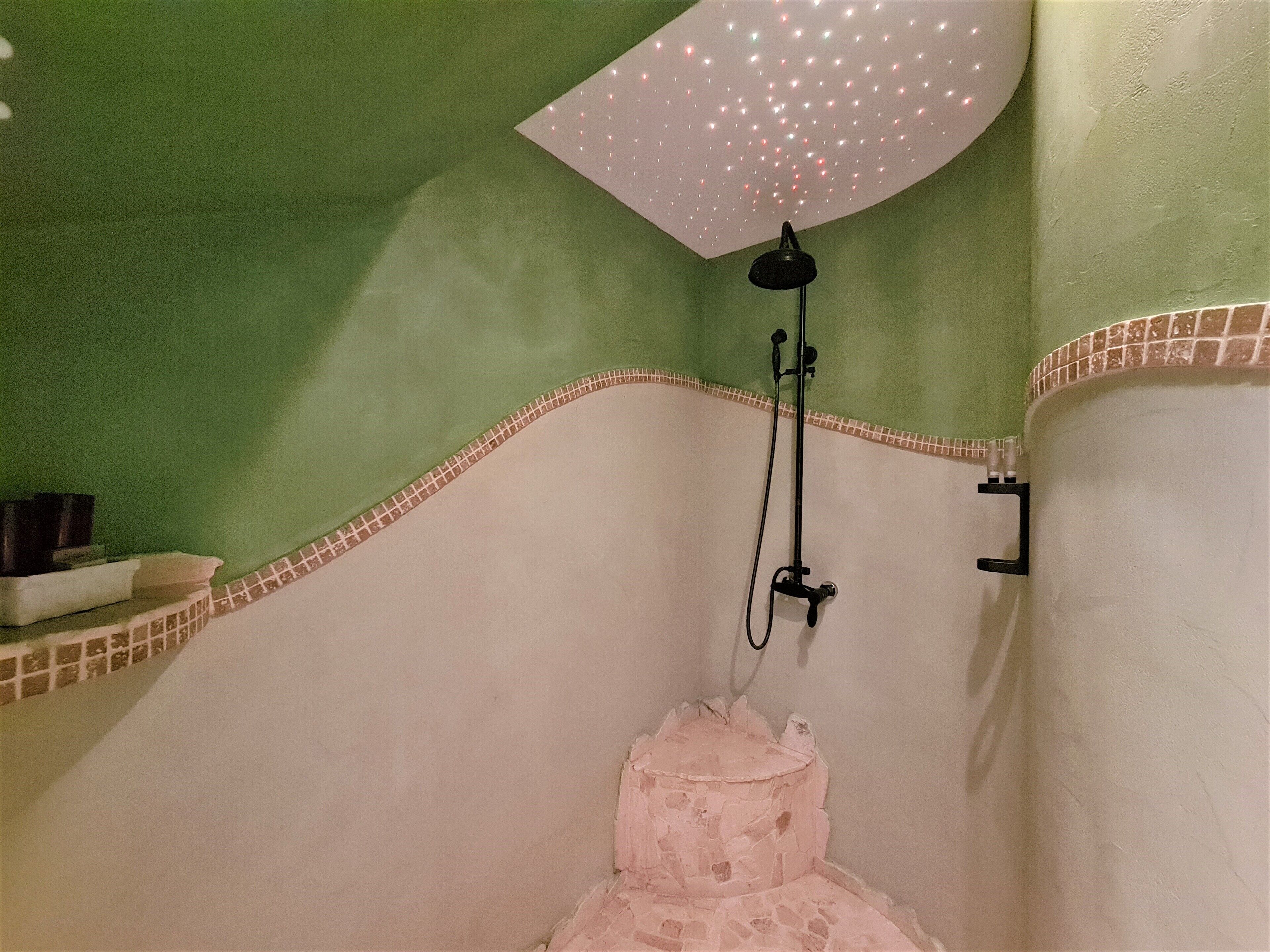 A bathroom with a shower, a towel rack, and a shelf with toiletries.