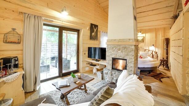 L’intérieur d’un chalet en bois chaleureux, doté d’une cheminée, d’un téléviseur et d’un coin salon confortable.