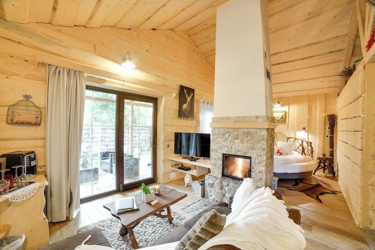 A cozy wooden cabin interior with a fireplace, a television, and a comfortable seating area.
