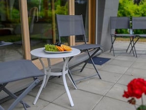 An outdoor seating area with a round table, two chairs, and a plate of fruit. - AquaPark Residence (Zakopane)