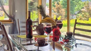Ein Esstisch mit einer Flasche Rotwein, einer Ananas, Bananen und roten Rosen.
