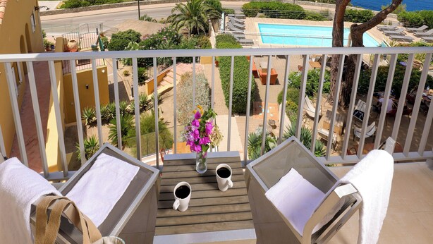 Un balcon avec vue sur la mer, une piscine et une table avec des chaises.