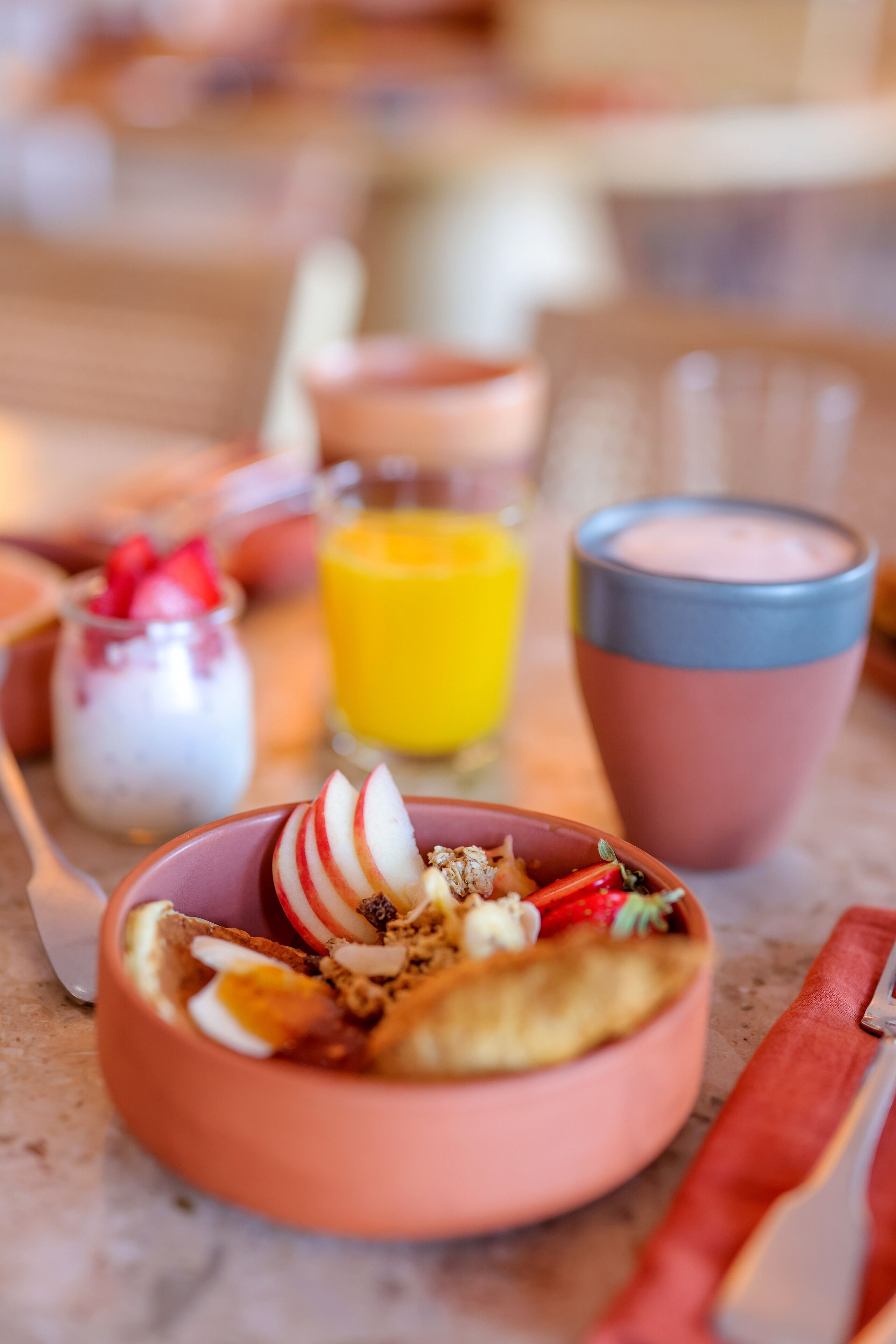 Un desayuno con un tazón de cereal, un vaso de jugo de naranja y una taza de leche.