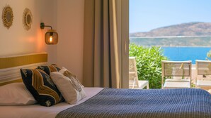 Une chambre d’hôtel avec un lit, des appliques murales décoratives et une vue sur la mer.