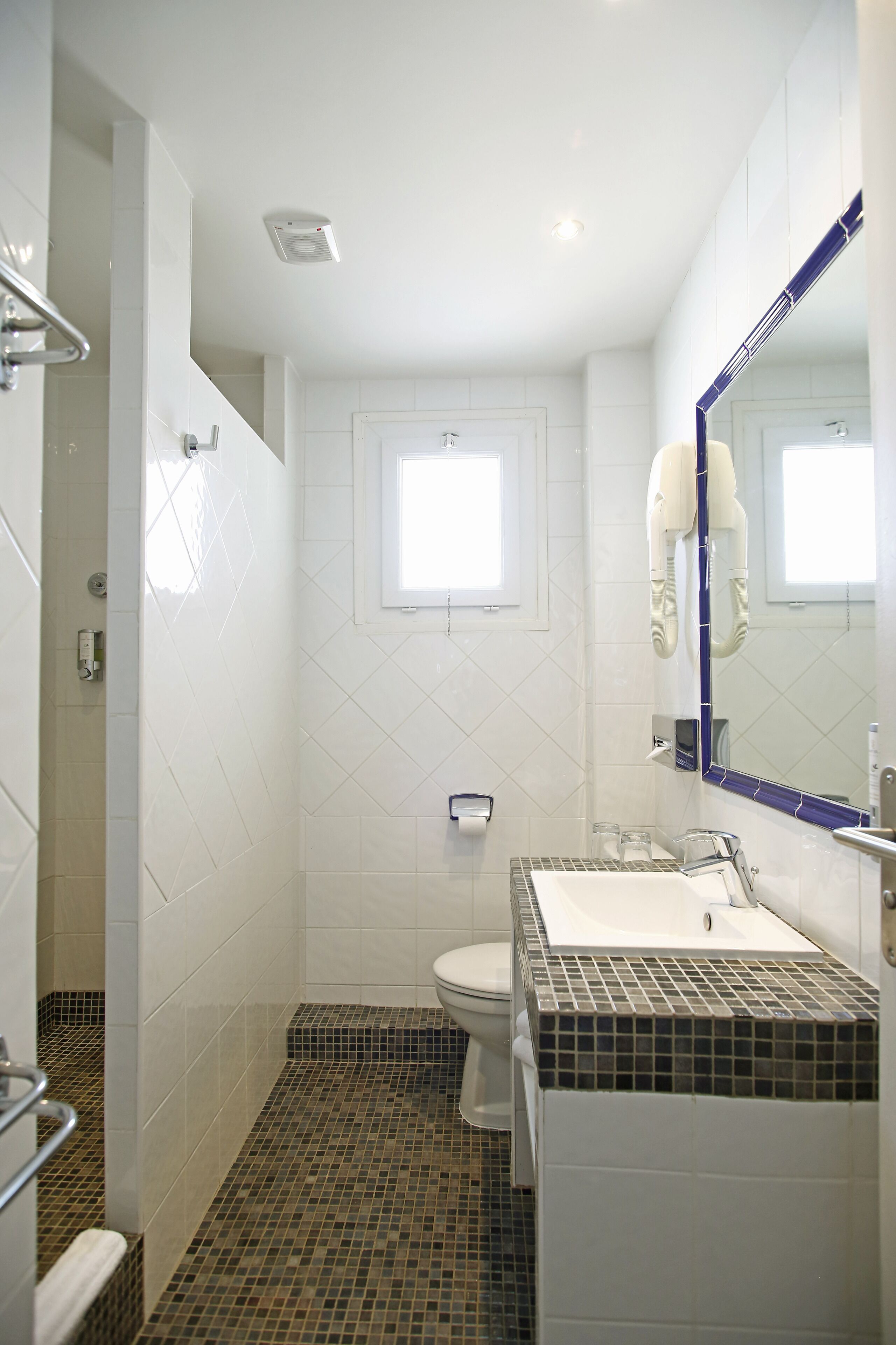 A bathroom with a white toilet, a sink with a mirror, and a shower area.
