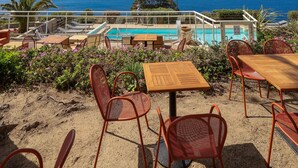 Un espace aménagé au bord de la piscine, avec des sièges extérieurs et une vue sur la mer.
