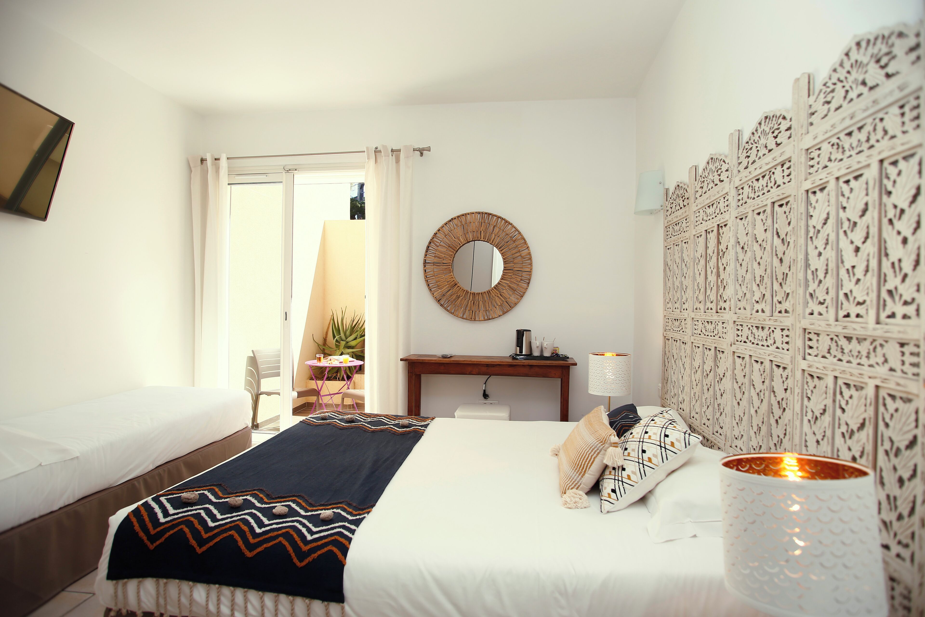 Un dormitorio con cama, mesita de noche, lámpara, espejo y un panel decorativo en la pared.