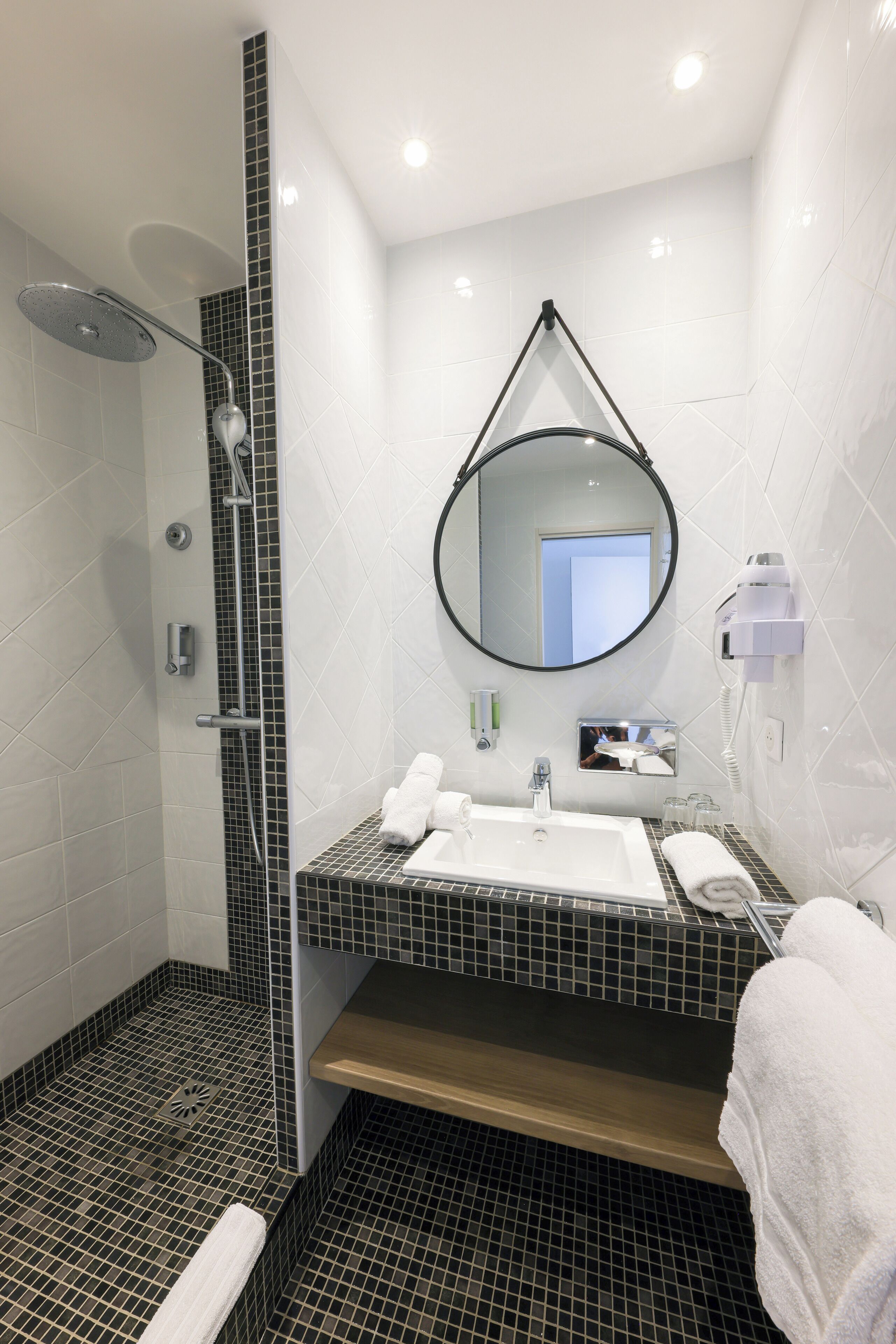 A modern bathroom with a shower, a sink, a mirror, and a towel rack.
