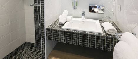 A modern bathroom with a shower, a sink, a mirror, and a towel rack.
