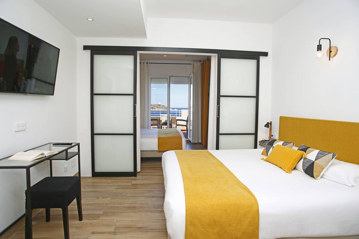Quarto de hotel moderno com cama, escrivaninha e televisão.