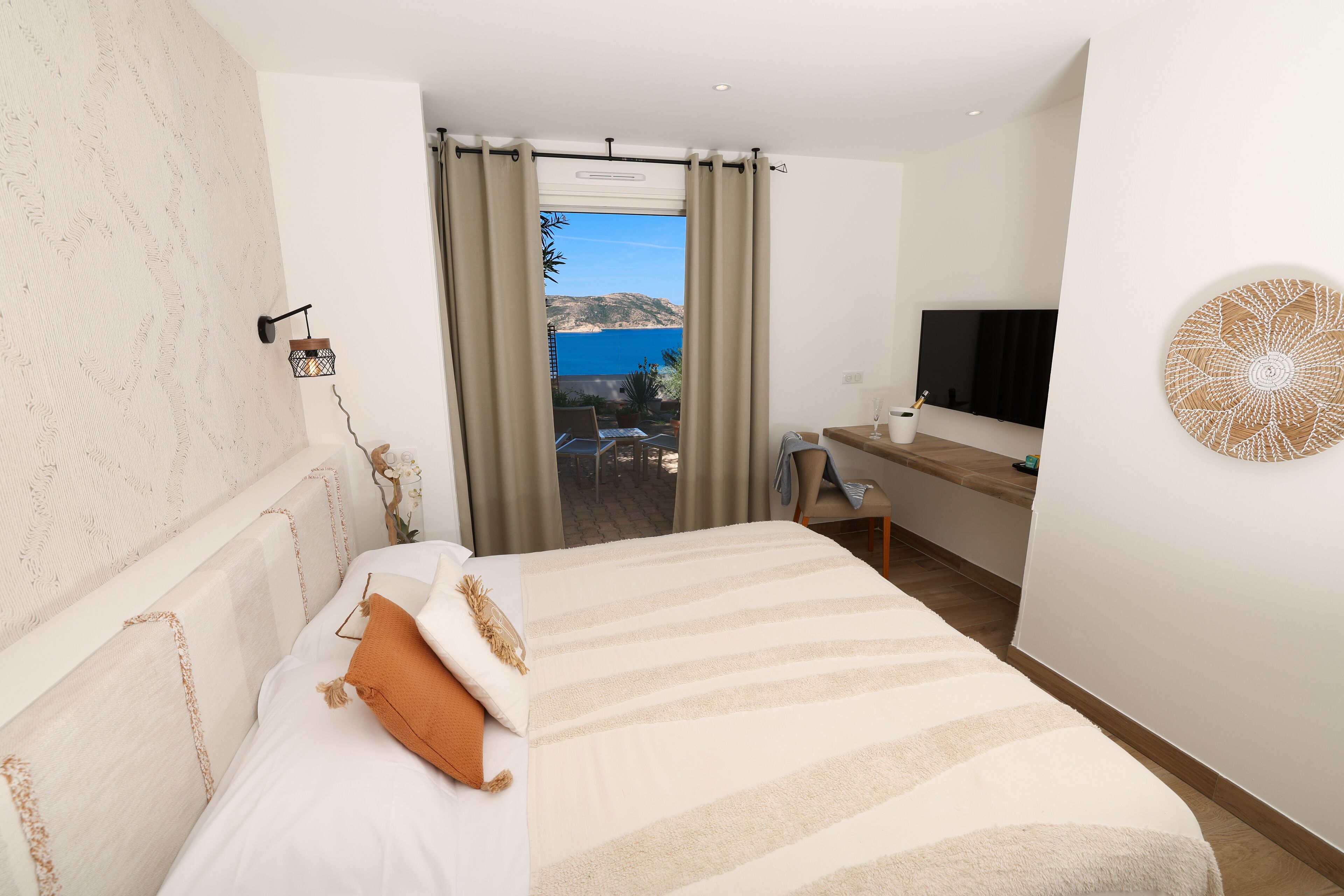 Un dormitorio con cama, escritorio, televisor y vista al mar.