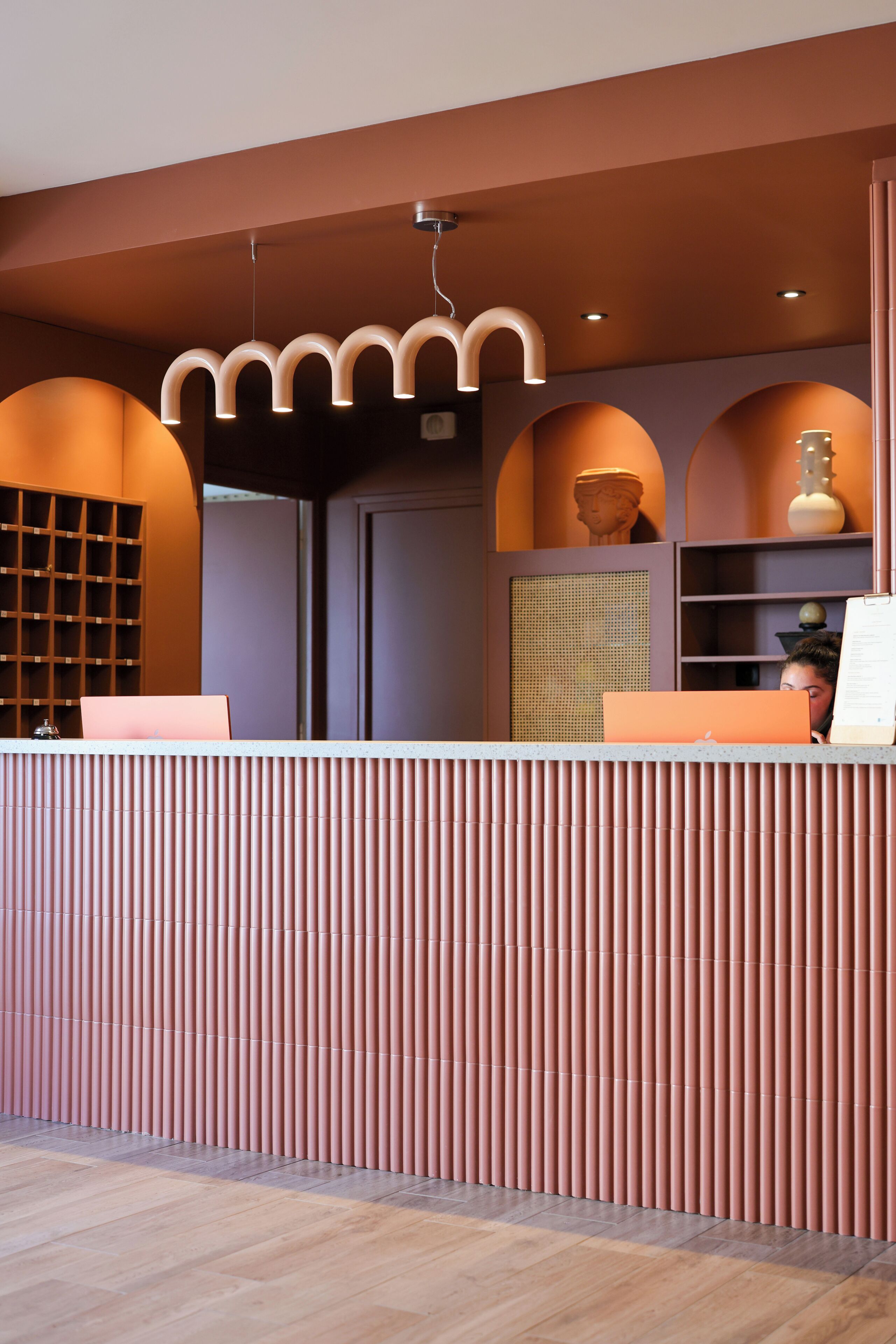 A reception desk with a modern design, a wooden floor, and a wall with a patterned design.