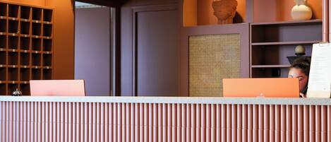 A reception desk with a modern design, a wooden floor, and a wall with a patterned design.