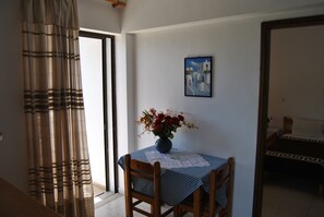 A room with a dining table set with a blue tablecloth, a vase of flowers, and a painting on the wall. - Stergia Apartments (Kos)