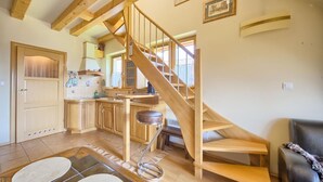A spacious living area with a wooden staircase, a kitchen with wooden cabinets, and a dining area with a bench. - VisitZakopane Vanilla Apartments (Koscielisko)
