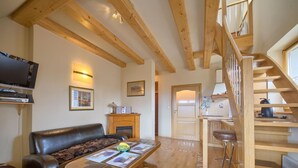 A living room with a wooden ceiling, a fireplace, a sofa, a coffee table, and a staircase. - VisitZakopane Vanilla Apartments (Koscielisko)