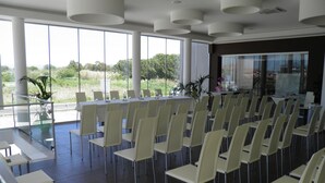 Un salón de conferencias con una larga mesa y sillas, ventanas amplias y vistas a zonas verdes exteriores.