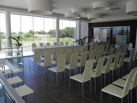 Uma sala de conferências com uma longa mesa e cadeiras, grandes janelas e vista para o verde lá fora.