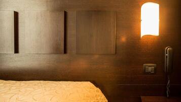 Una habitación de hotel con una cama, un teléfono en la mesita de noche y lámparas fijadas a la pared.