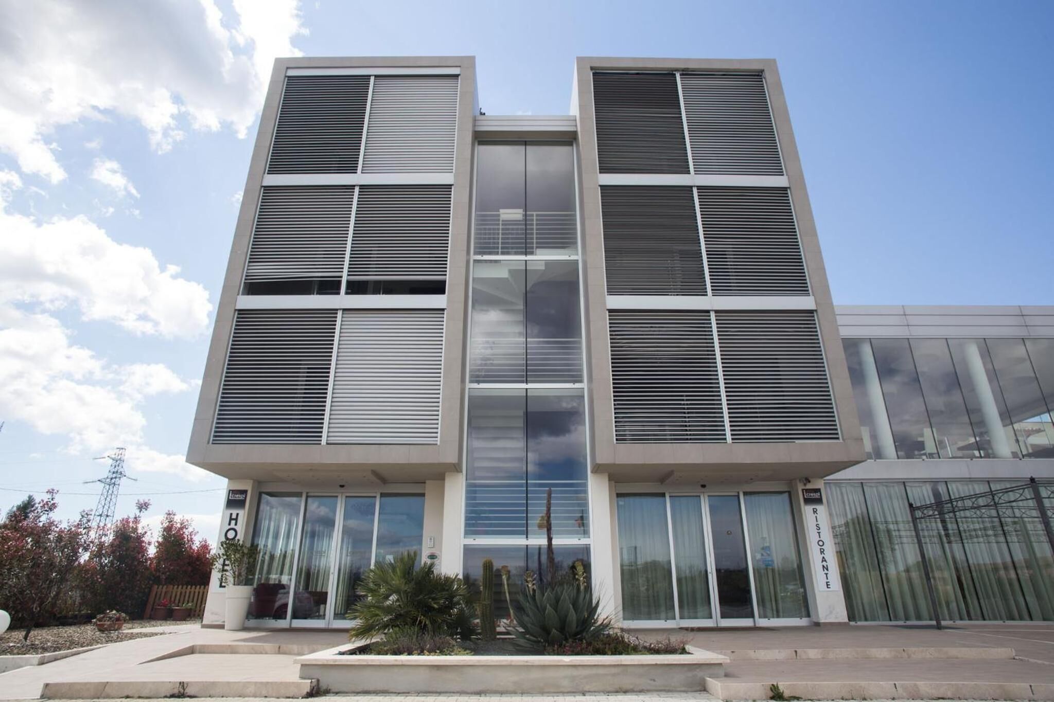 Un hôtel moderne à la façade symétrique, doté de grandes fenêtres et d’une entrée centrale.