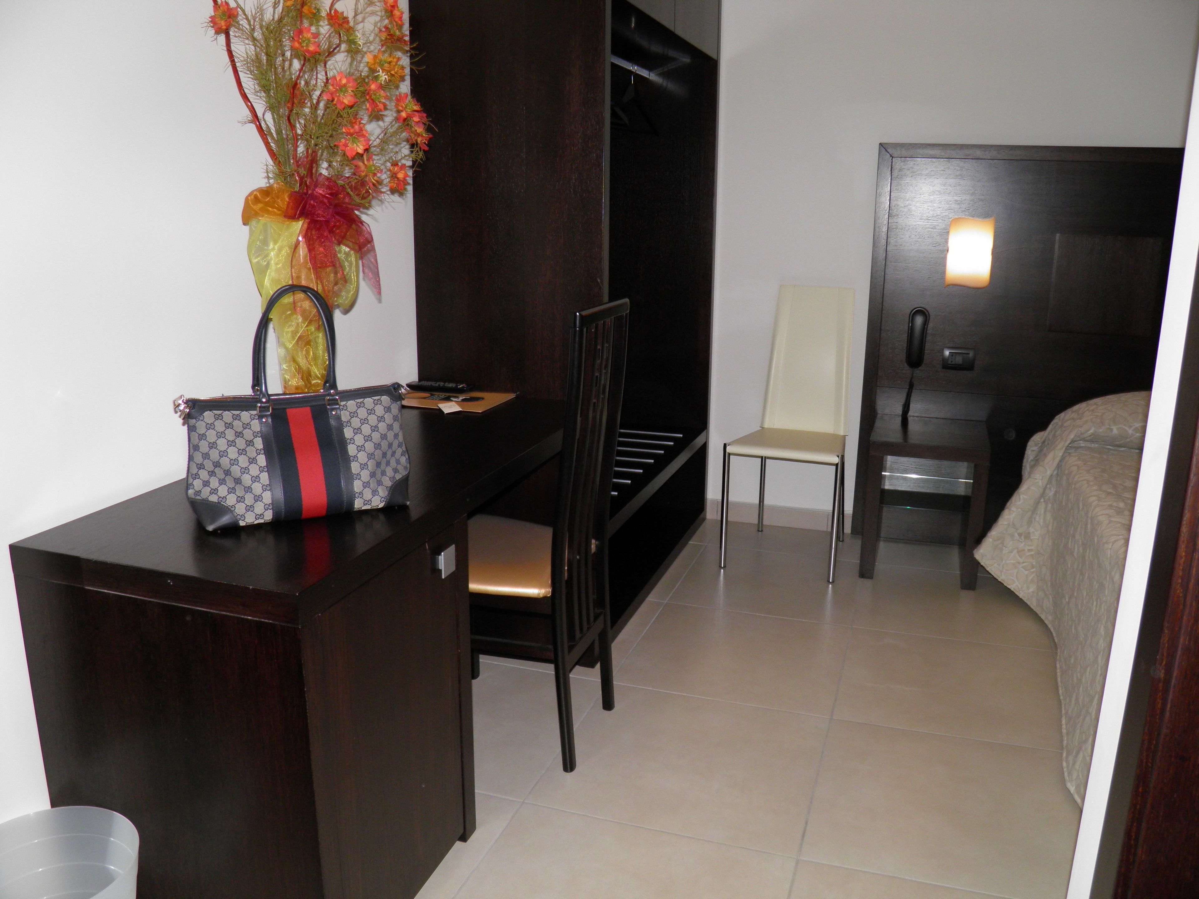 A hotel room with a desk, a chair, a bed, a TV, and a telephone.