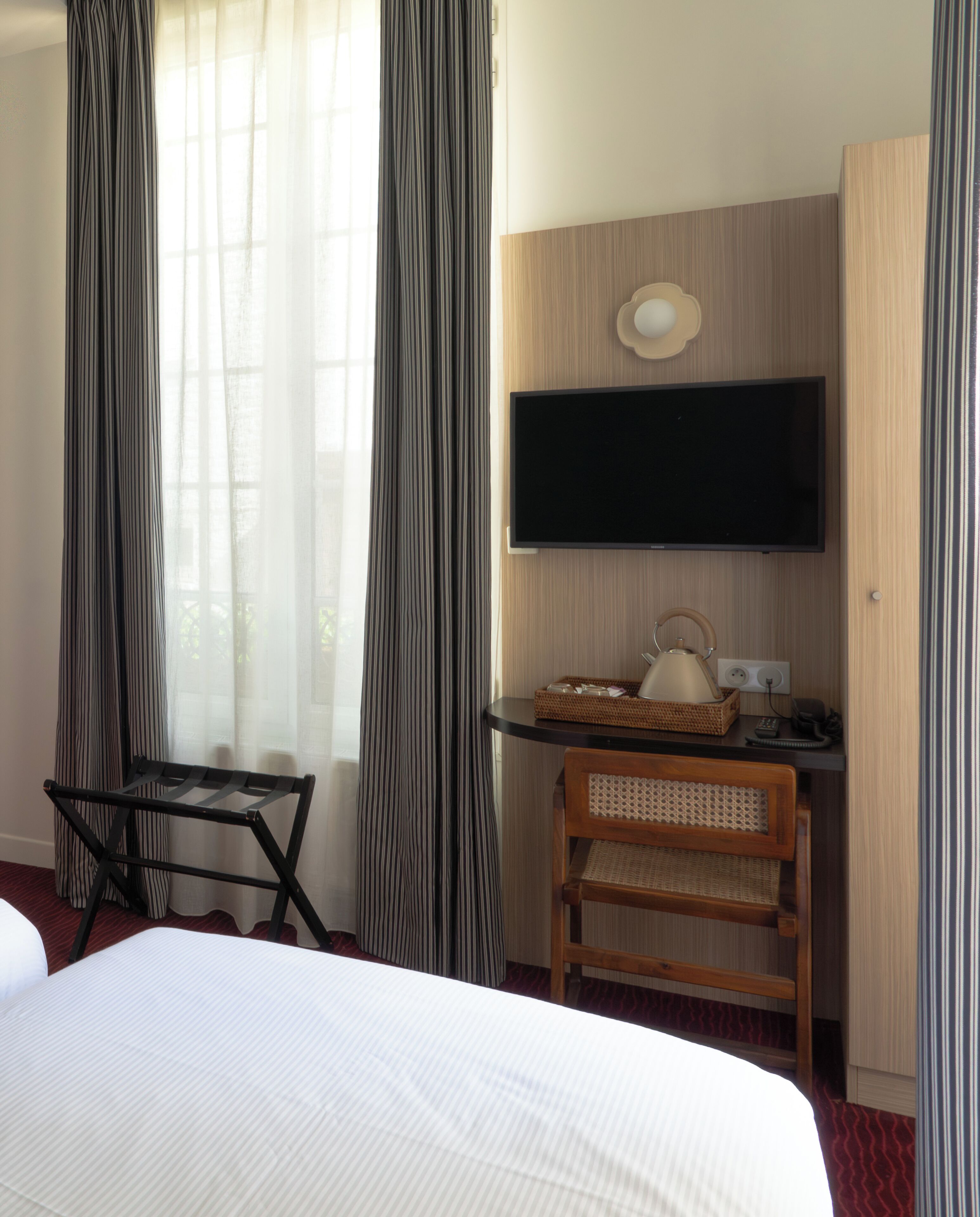Une chambre d’hôtel comprenant un lit, un bureau avec un téléviseur à écran plat, une lampe et une chaise.