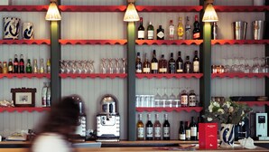 A bar area with shelves of bottles and glasses, a coffee machine, and three stools. - Marnie House Hôtel (Le Touquet-Paris-Plage)