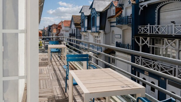 A balcony with wooden flooring, blue chairs, and a table. - Marnie House Hôtel (Le Touquet-Paris-Plage)