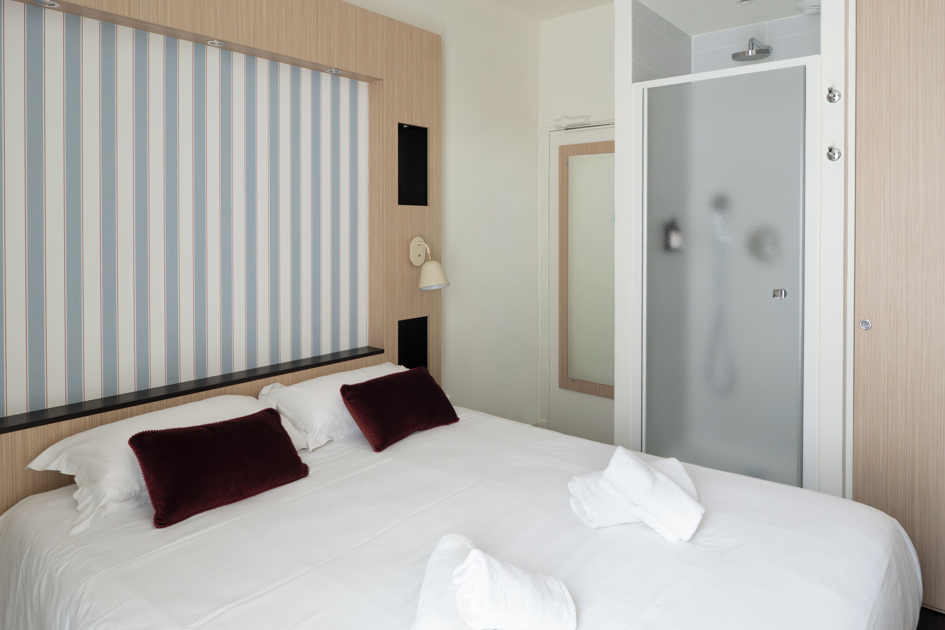 Une chambre d’hôtel avec un lit, une douche et un mur à rayures.