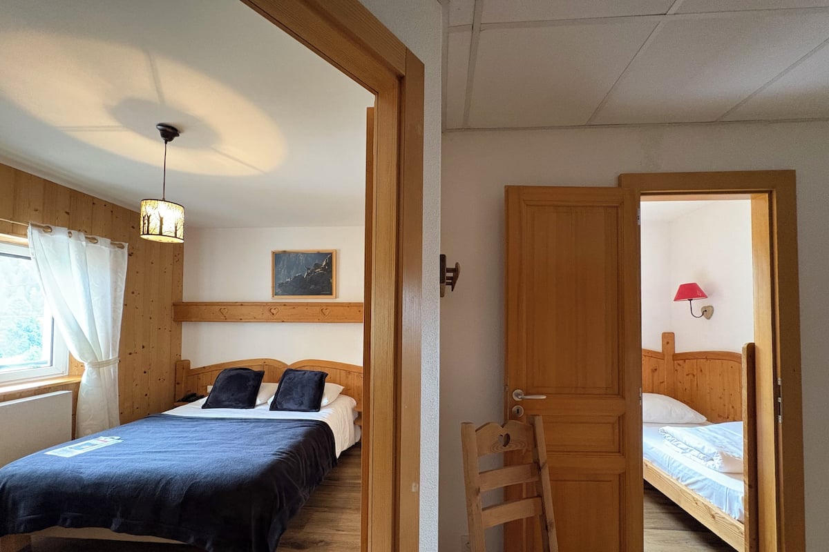 Una habitación con una cama, una silla, una puerta y una mesita.