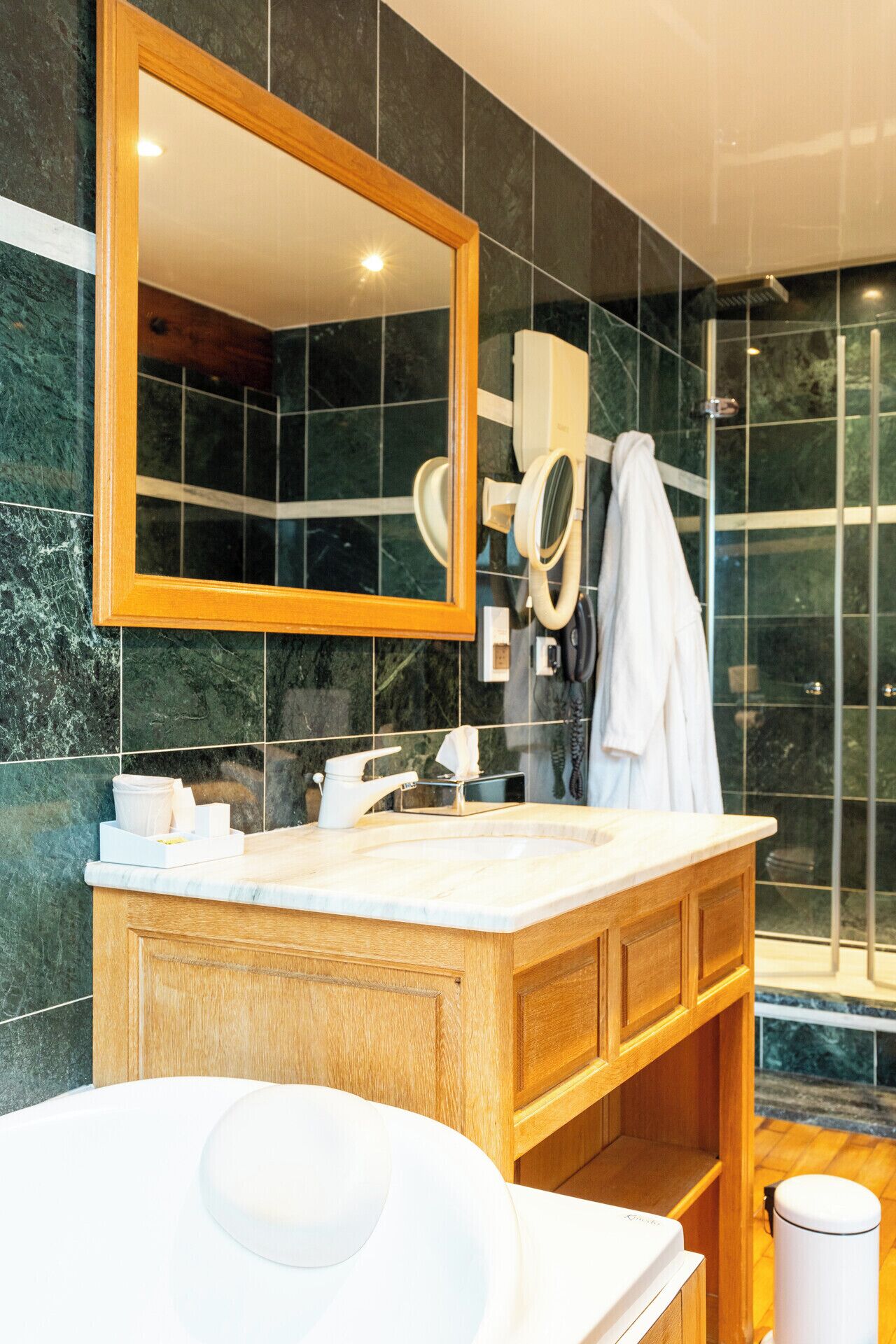 A modern bathroom with a wooden vanity, a large mirror, a glass shower enclosure, and a white bathtub.