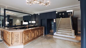 A spacious kitchen with a large island, dark blue cabinetry, and a modern chandelier.