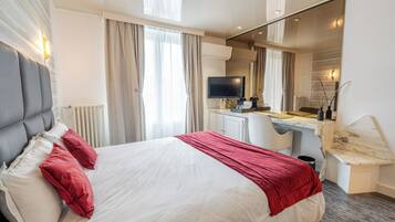 Una habitación de hotel con cama, escritorio, televisión y espejo.