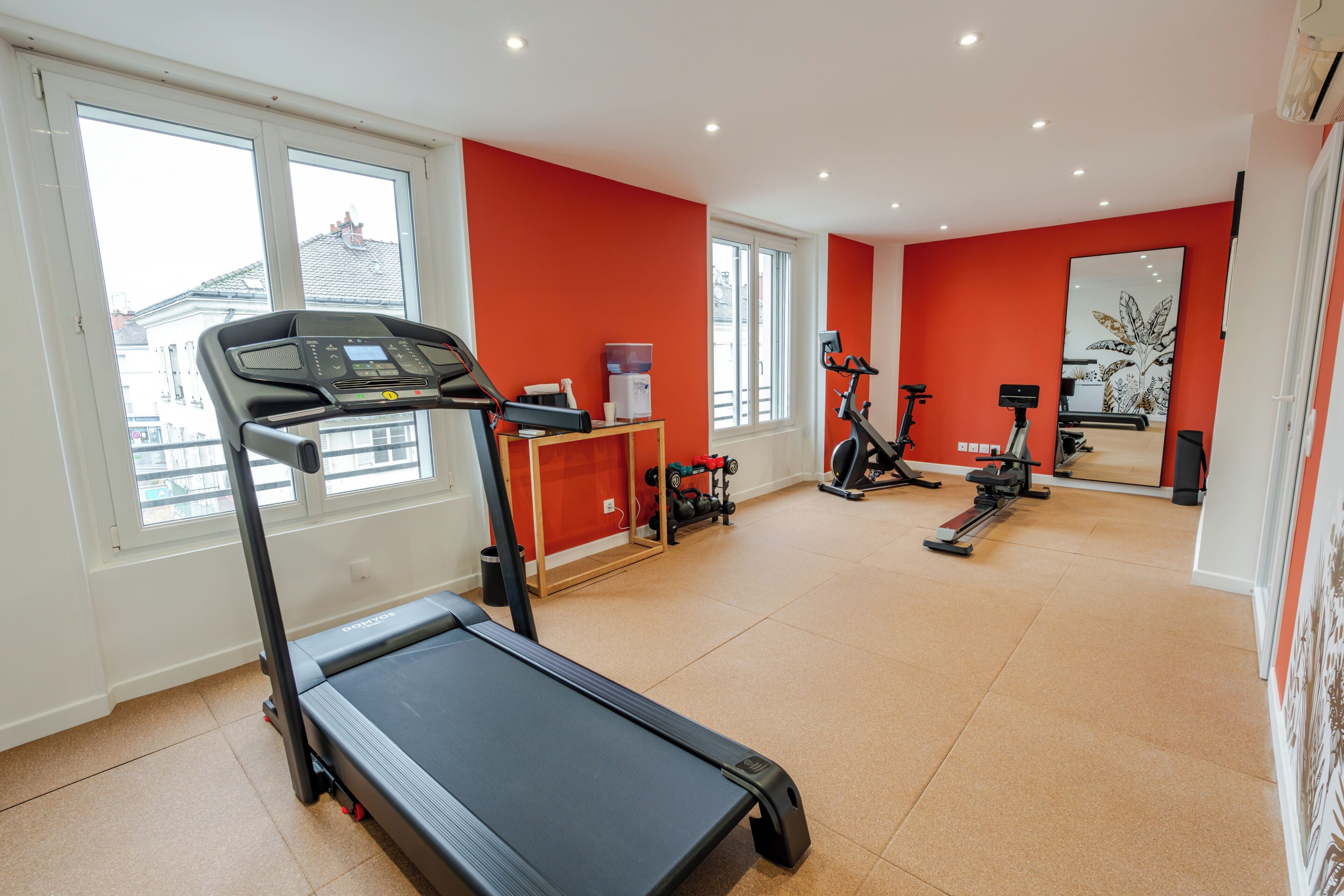 A gym with a treadmill, exercise bikes, and weights.