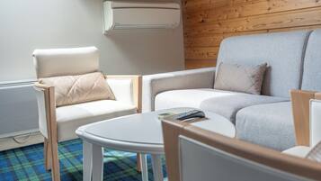 Un salon moderne avec un canapé gris, un fauteuil blanc et une petite table blanche.