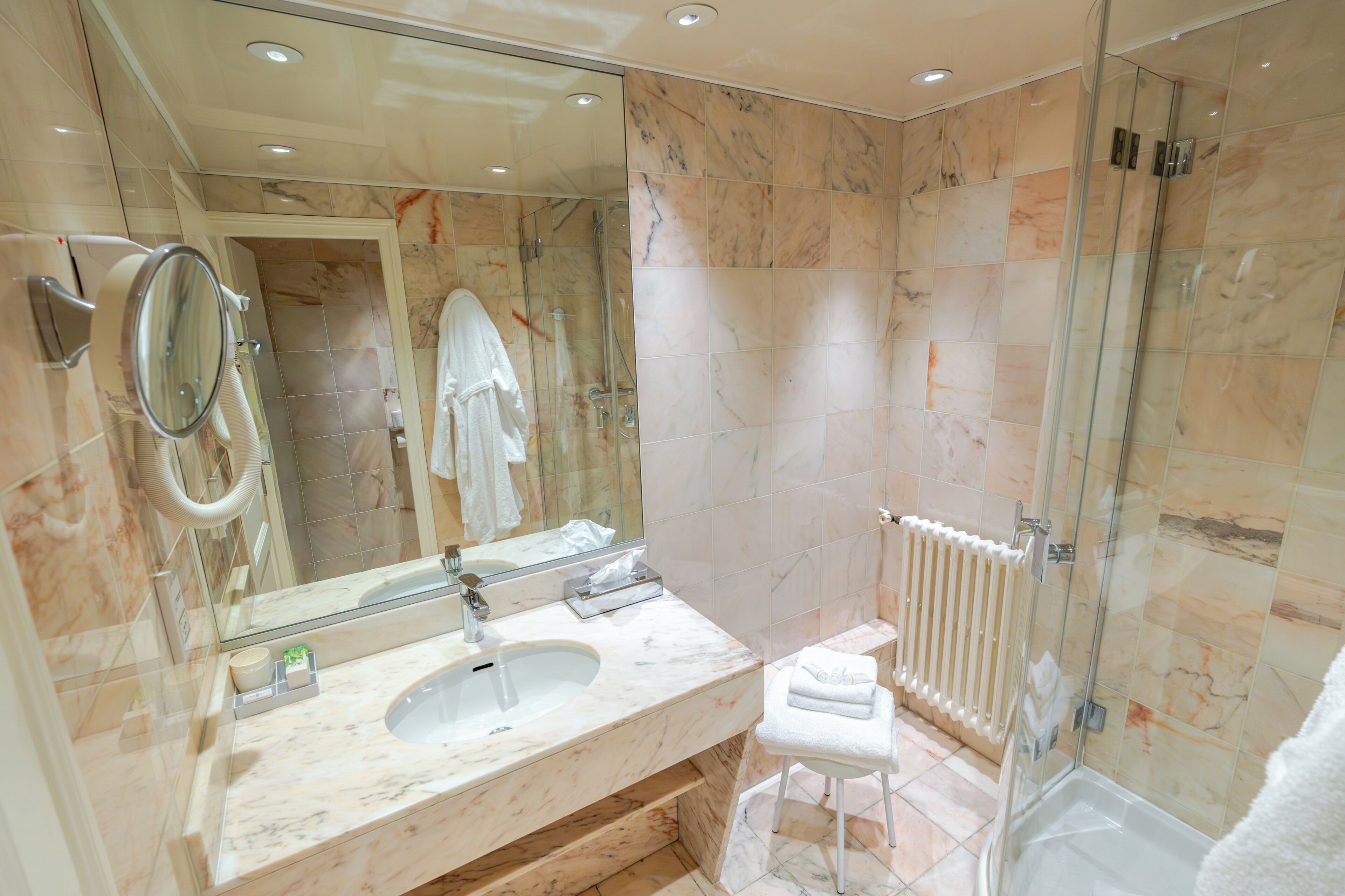 A modern bathroom with a marble sink, a glass shower enclosure, and a white towel.