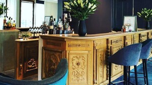 A bar area with a wooden counter, bar stools, and a large mirror.
